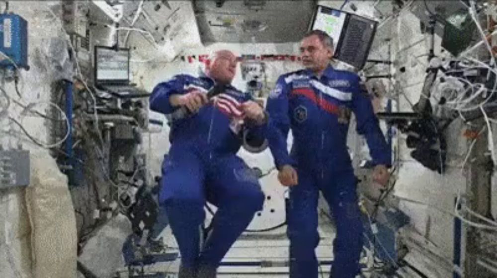 two men in blue space suits are dancing in a room .