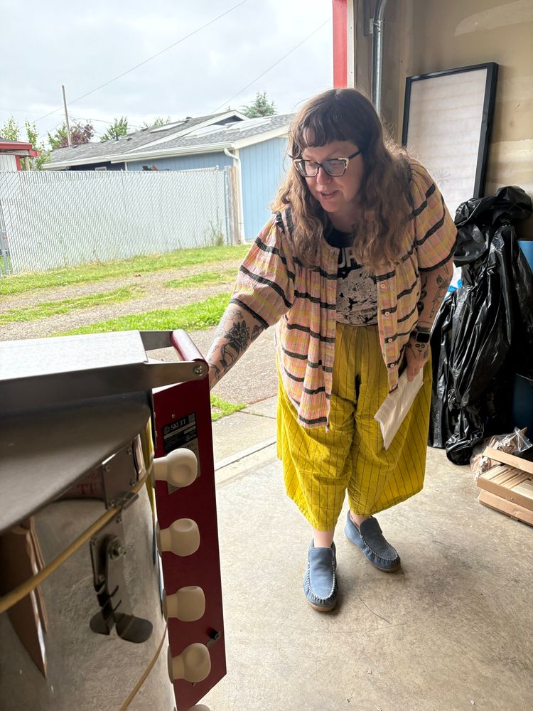 Middle aged white woman in an outlandish outfit leaning over to program her skutt 1027 ceramics kiln