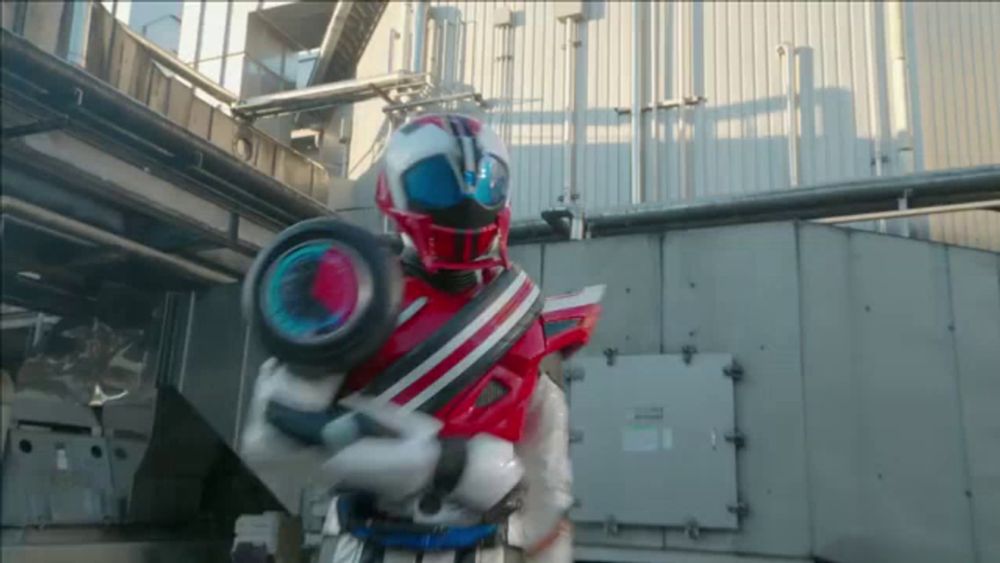 a man in a red and white motorcycle costume is holding a large wheel .