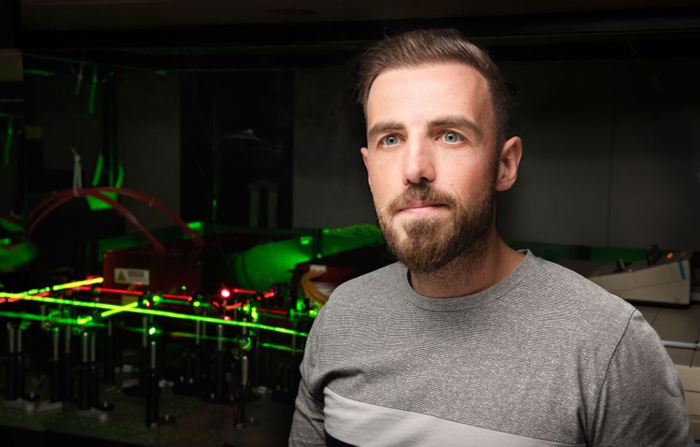 Grad Student in front of CARS Laser Setup in his lab