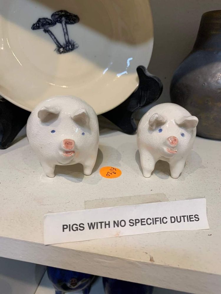 Photo of small ceramic pig sculptures labeled “pigs with no specific duties”
