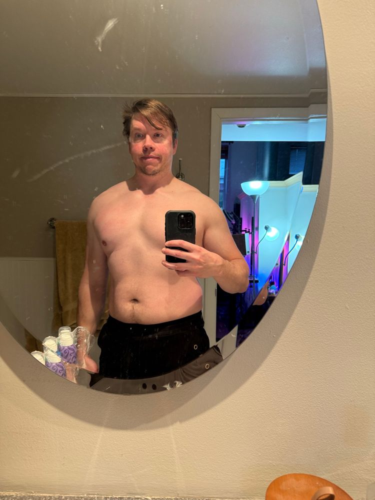 The poster, shirtless, in a round bathroom mirror 