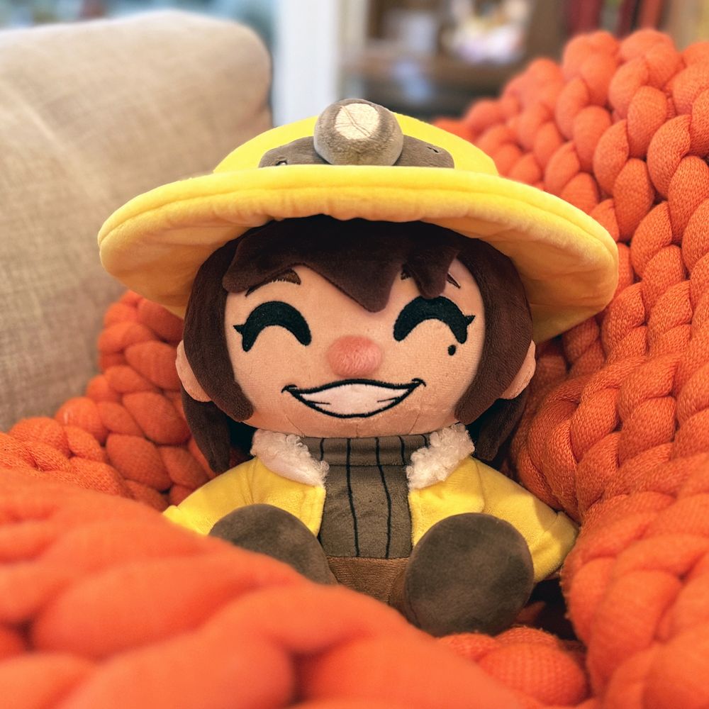 Ana Spelunky Youtooz plush relaxing in an orange blanket.
