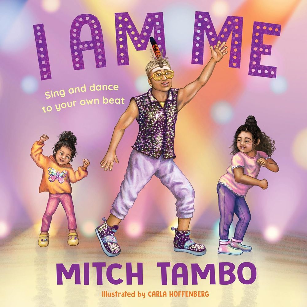 Cover image of Mitch Tambo's picture book I Am Me, showing Mitch Tambo dancing in the centre of the image, with a young Aboriginal girl dancing on either side of him.