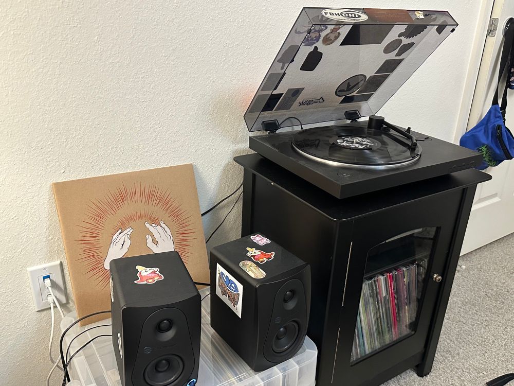 Album being played on a turntable. The album selected is “Lift Your Skinny Fists Like Antennae to Heaven” by Godspeed You! Black Emperor, a post-rock album. 