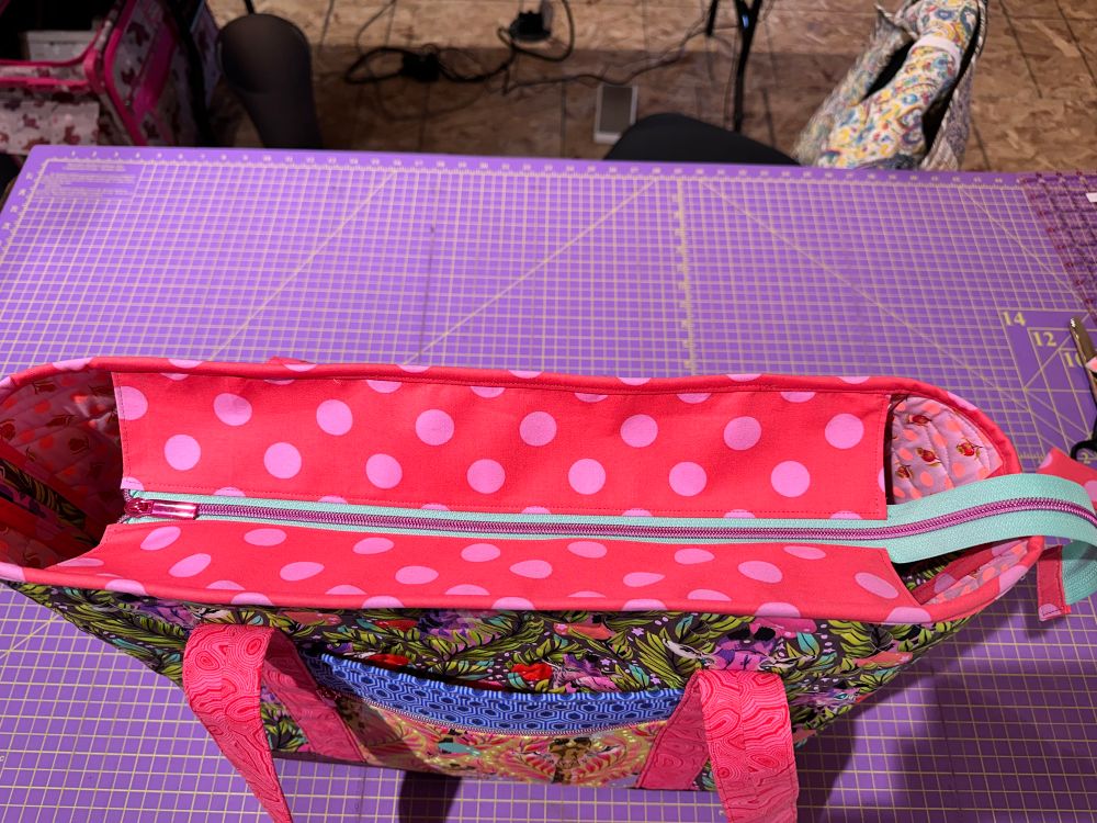 Top of tote, with a pink metallic zipper on teal green zipper tape. 