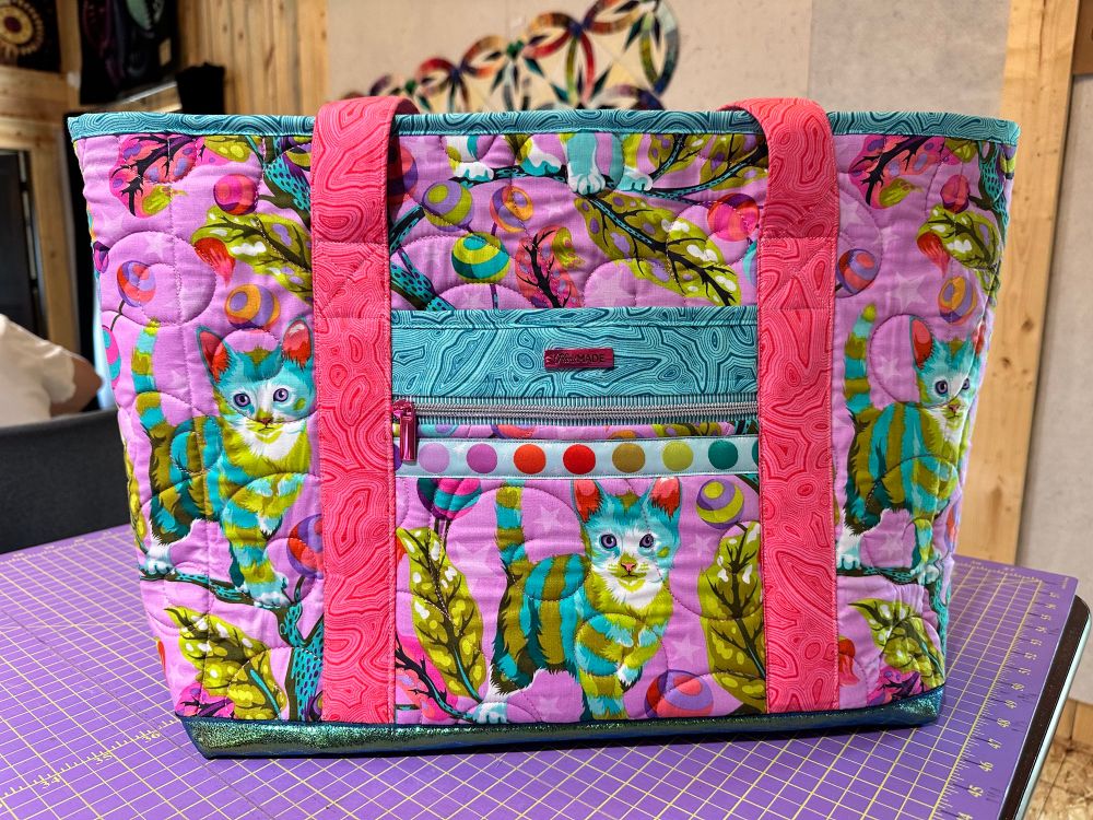 Front has a zipper pocket and a slip pocket, with ribbon trim