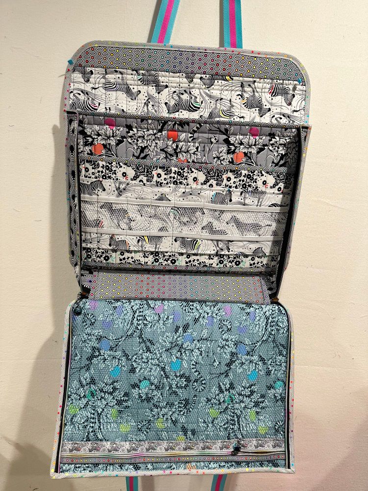 Inside has a full size mesh zipper pocket on the inside of the front. The back has a 3-layer divider to hold quilting tools 