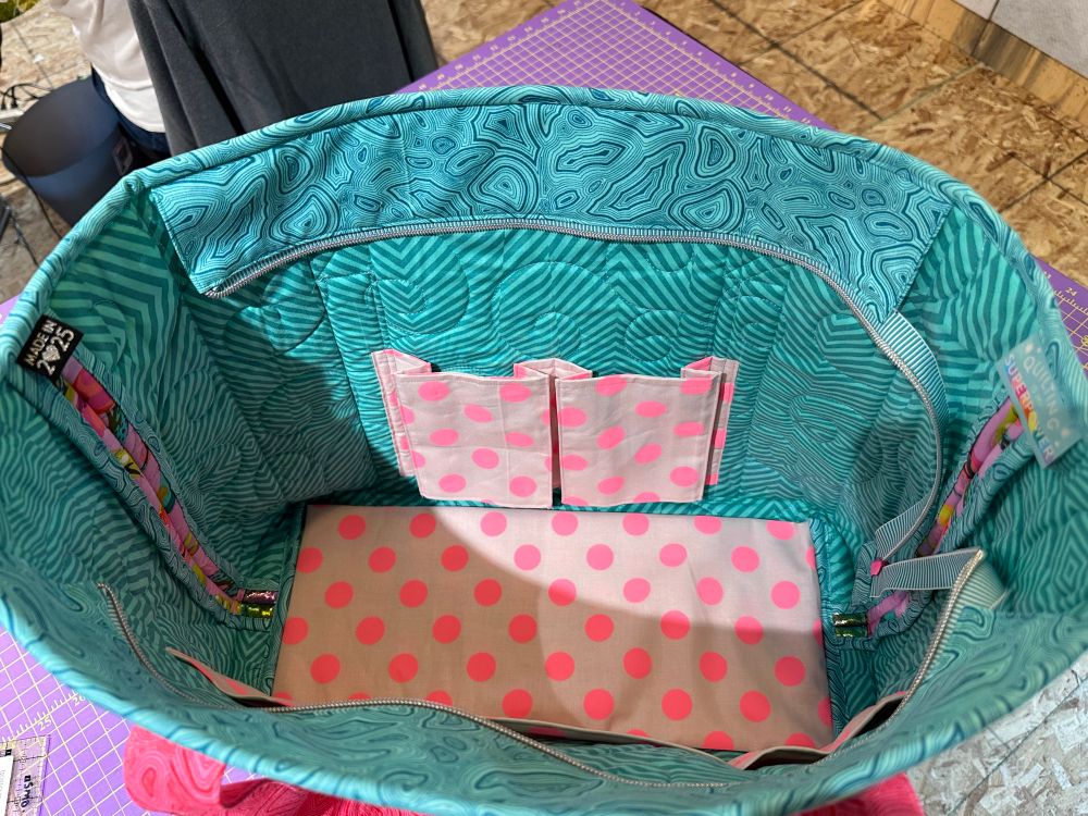 Hard base on the inside. Bellowed pockets (to hold a water bottle upright) on one side, and a divided slip pocket on the other side