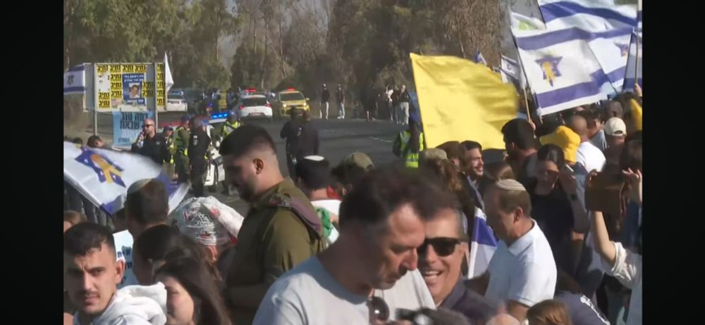 Eine Menschenmenge steht an der Straße und wartet auf befreite Geiseln.