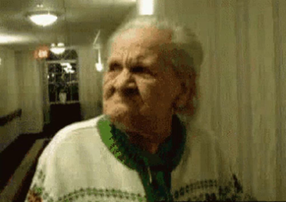 an elderly woman in a green and white sweater is making a funny face