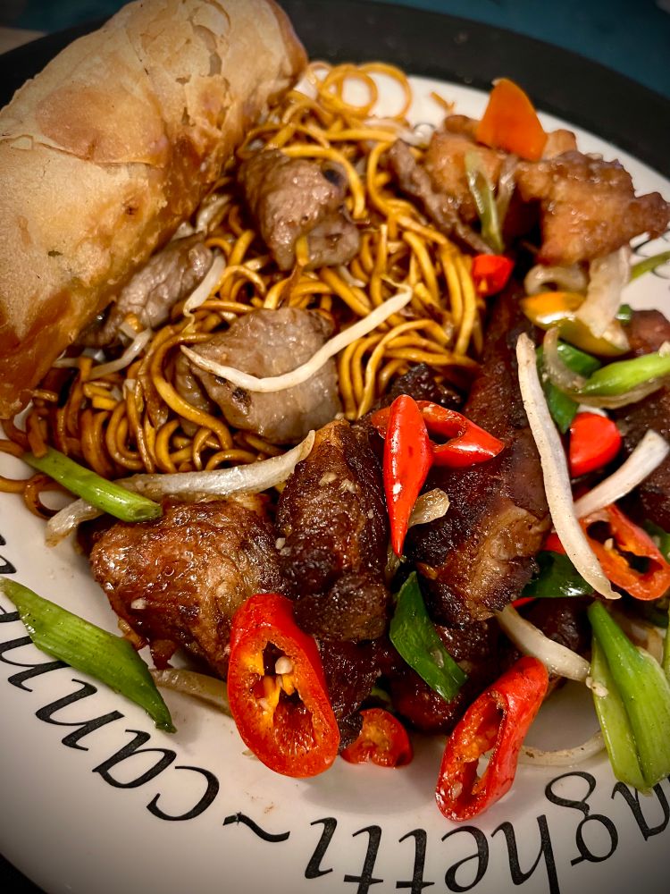 A huge plate of ribs, noodles, chilis, and spring roll. 