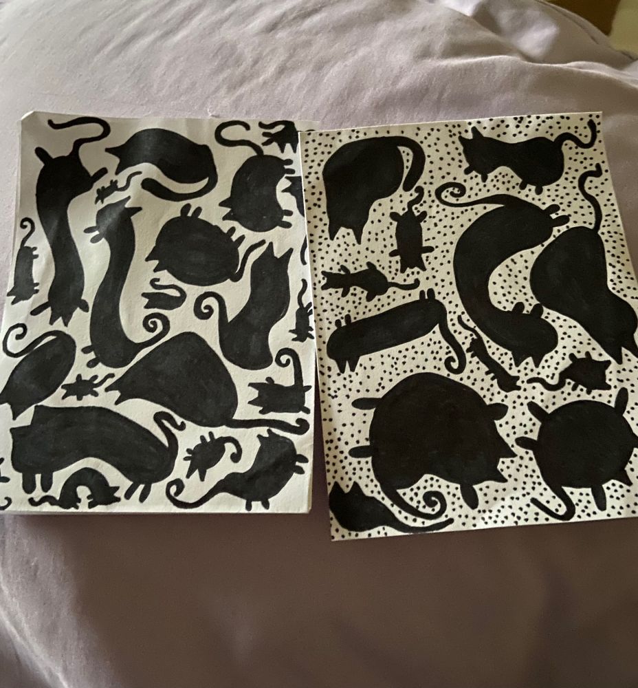 Two pieces of paper with black cats drawn as blobs in sharpie. The one on the right has dots filling in the white space between the blob cats.