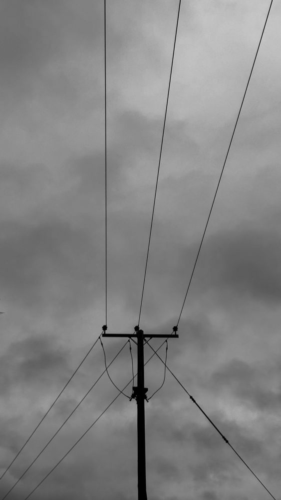 Monochrome of television pole and wires against clouds 