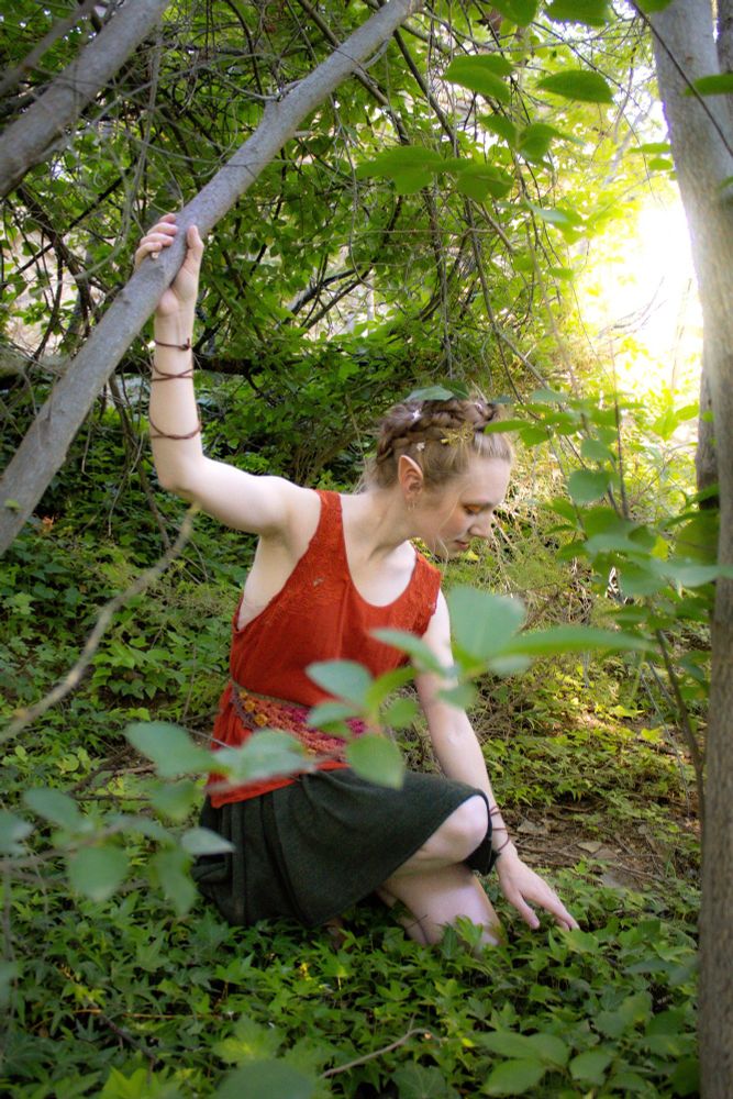 Me dressed as a fairy crouching in the forest