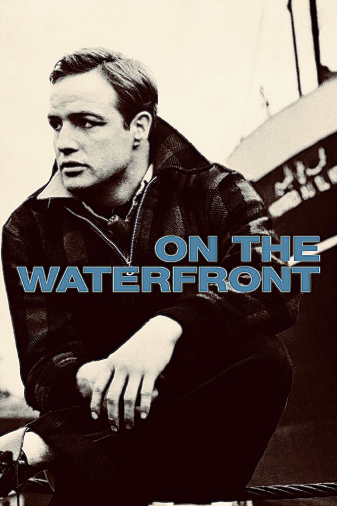 Poster for On The Waterfront. A man (Marlon Brando) in a black jacket squatting in front of a large ship looks off into the distance 