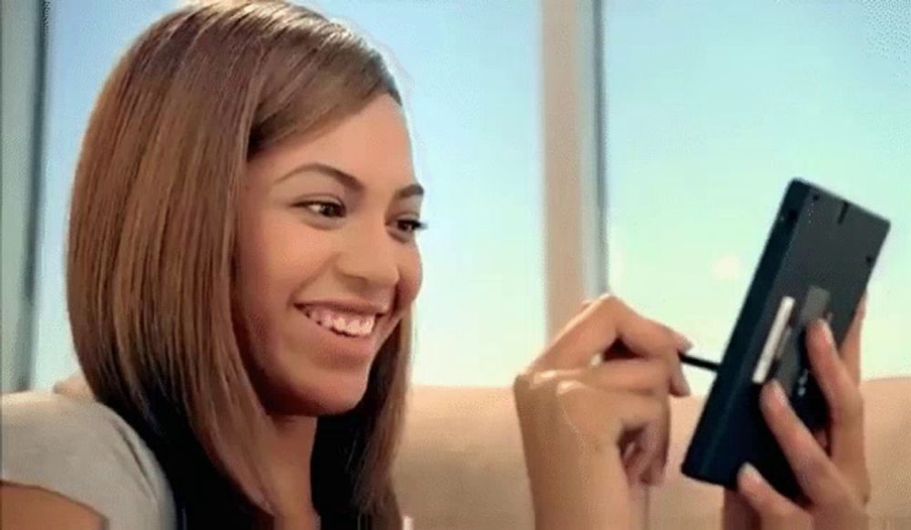 a woman is sitting on a couch looking at herself in a mirror and smiling