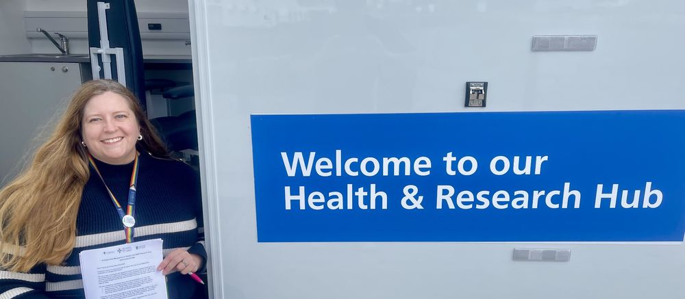 A woman standing near the open door of a research bus holding a piece of paper