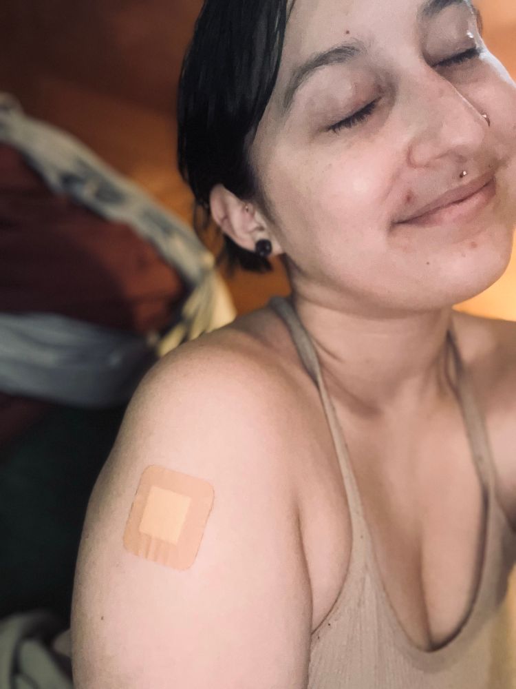 A selfie, I have dark hair tied up, eyes closed, a bandaid on my arm