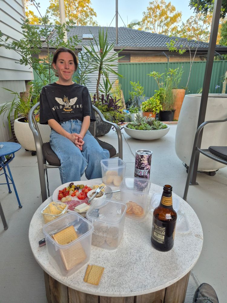 A freshly painted patio with seats around a small table. A platter of antipasti and a variety of crackers are there for the taking. 
