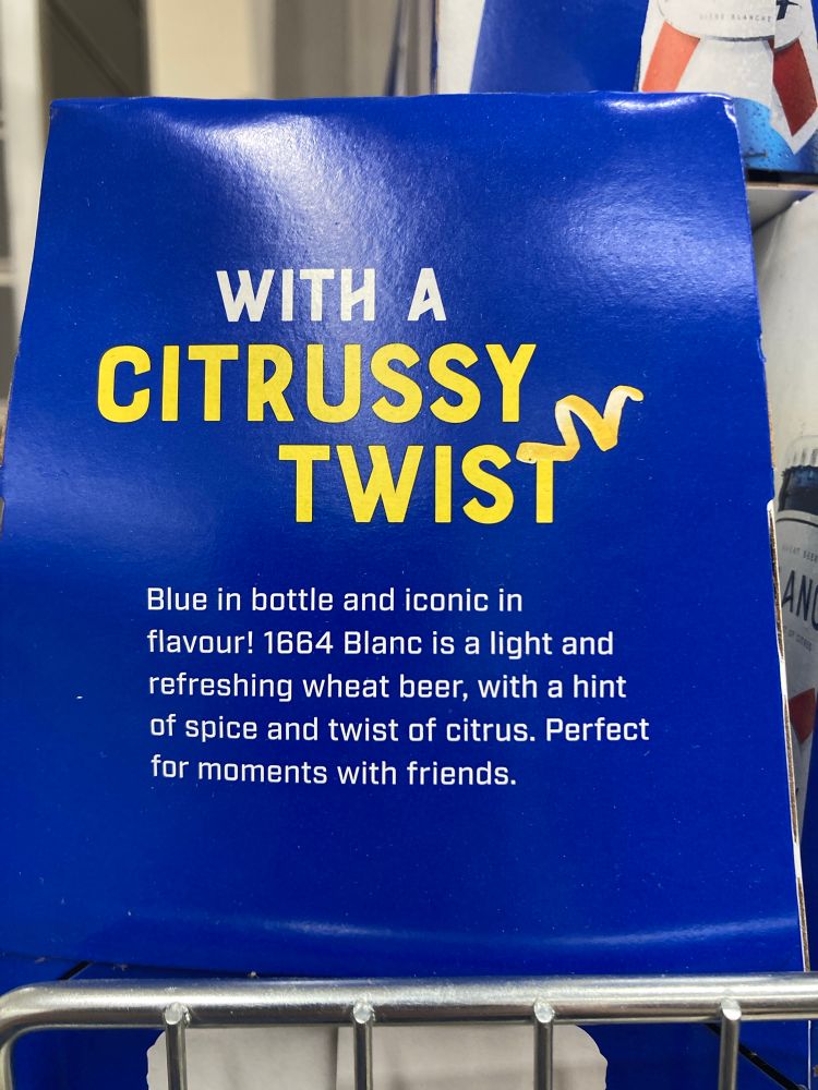 The side of a beer box. It reads: 

With a citrussy twist. 

Blue in bottle and iconic in flavour! 1664 Blanc is a light and refreshing wheat beer, with a hint of spice and a twist of citrus. Perfect for moments with friends. 