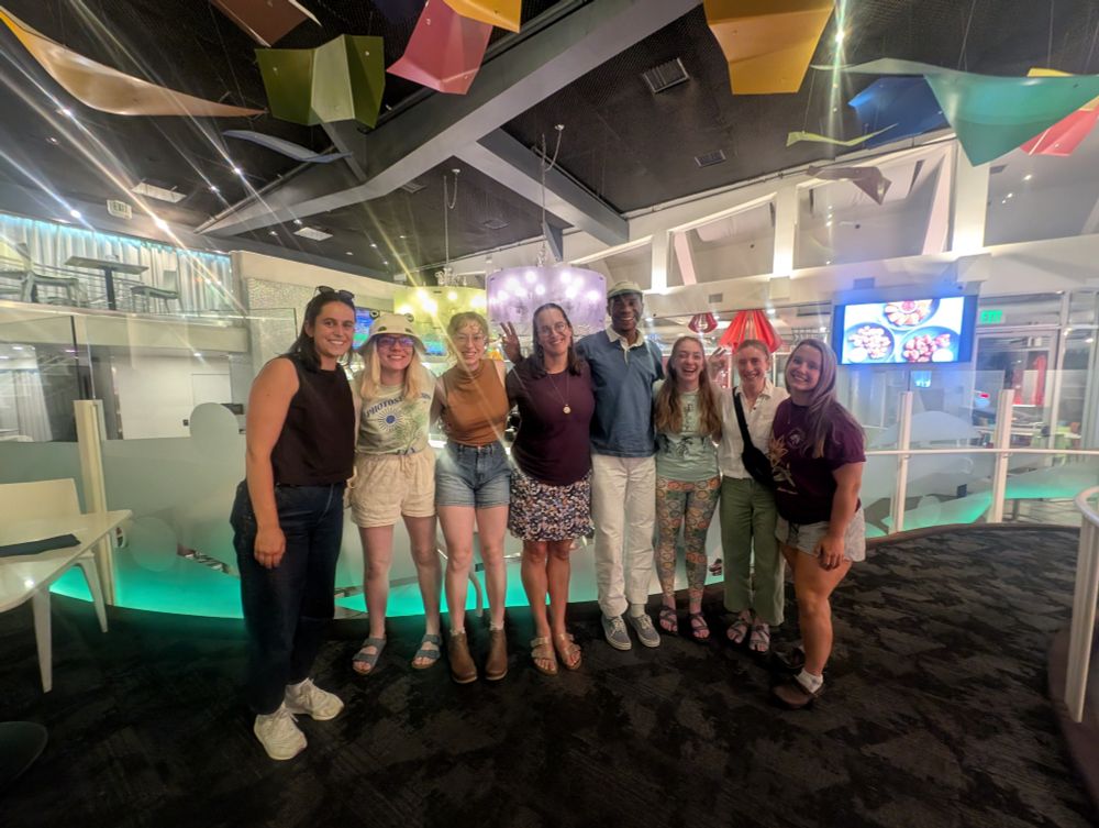 Eight people in a line smiling 