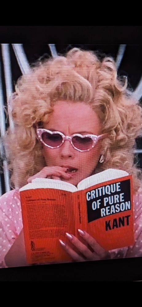 A woman in heart glasses reading Kant (an image taken from Superman 3)