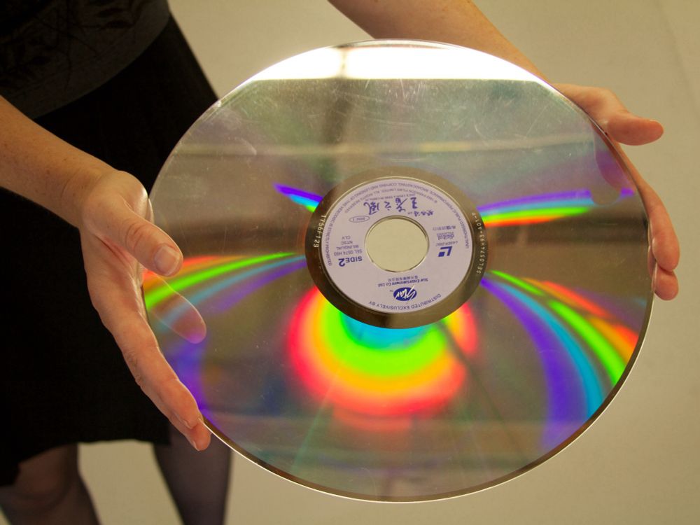 Advertisement photo: woman’s hands holding a Laserdisc. Rainbow refections on the disk.
