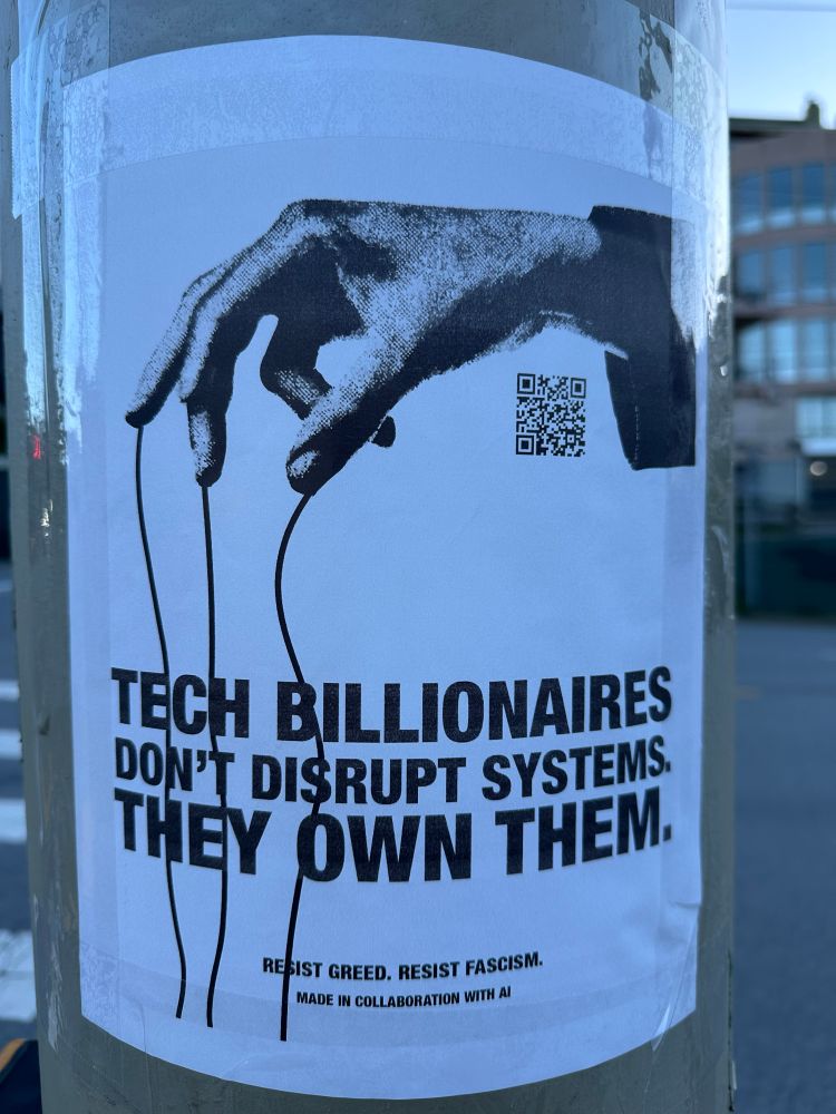 An flyer taped to a telephone pole. The flyer has a black and white grainy hand with a suit cuff visible, dangling strings that go down the page. In all caps san serif under the hand it reads ‘tech billionaires don’t disrupt systems. They own them.’ In smaller text at the bottom of the page it says ‘resist greed. Resist fascism.’ Underneath that it says ‘made in collaboration with AI’
