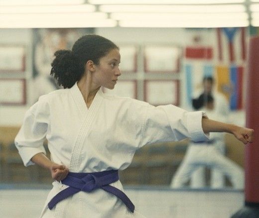 Girl in a kimono posing practicing karate in a dojo.