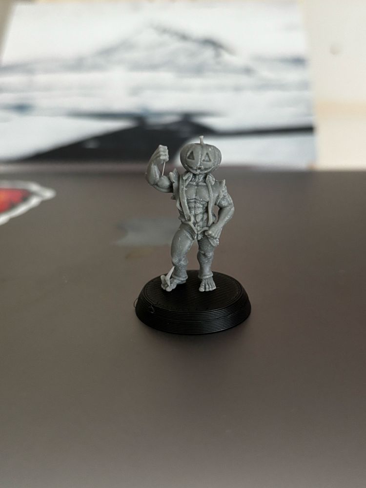 Small 3D printed gaming miniature of what can only be described as an extremely buff Jack Pumpkinhead wearing an open shirt with many, many defined abs on show