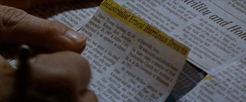 Screen still from the movie "Conspiracy Theory." In this scene, the main character cuts a section of newspaper, the headline highlighted in yellow highlighter.