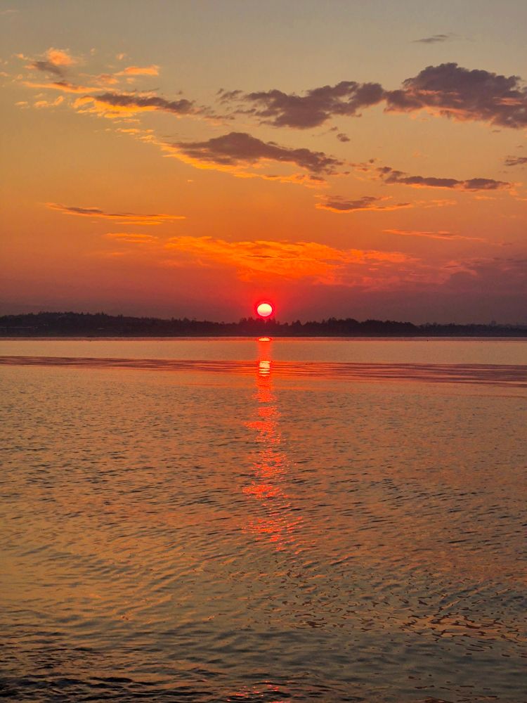 Sunrise over the Pacific Ocean off the coast of Vancouver Island. Wildfire smoke makes the sun look red as it rises. 