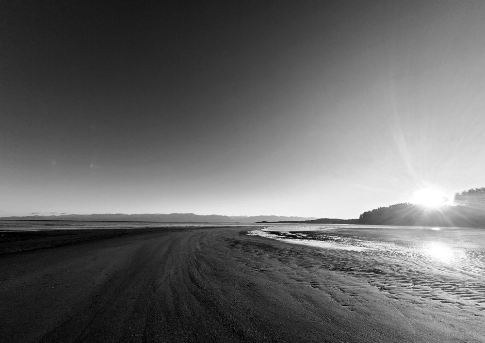 Black and white photograph of the sandy shoreline of Vancouver Island. 