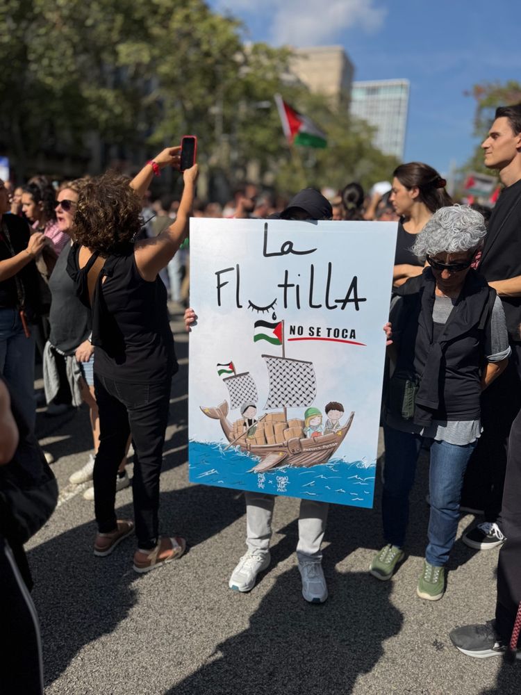 As imagens registram uma manifestação em apoio ao povo palestino, com forte presença de cartazes e bandeiras. Em uma delas, um cartaz diz: “Hay que callar cuando los niños duermen, no cuando los asesinan”, denunciando a violência contra crianças. Outra mostra uma criança nos ombros de um adulto erguendo a bandeira da Palestina, simbolizando resistência e futuro. Há também cartazes em catalão como “Els criminals de guerra al TRÍ” e “El crit de Gaza és el crit del món”, relacionando Gaza à denúncia global. Um quarto cartaz traz ilustração de um barco com a inscrição “La flotilla no se toca”, reforçando solidariedade e defesa da causa palestina. O ambiente revela uma multidão diversa, engajada em um protesto pacífico e expressivo.