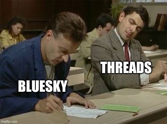 A imagem é um meme baseado em uma cena do personagem Mr. Bean em uma sala de aula. À esquerda, há um homem que parece concentrado escrevendo, com a palavra “BLUESKY” sobreposta à sua figura. À direita, Mr. Bean está olhando para a folha do homem ao lado, claramente tentando copiar, com a palavra “THREADS” sobreposta à sua figura. O meme sugere de forma humorística que Threads estaria “copiando” ideias ou estratégias de Bluesky.