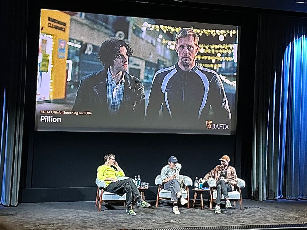 Alexander Skarsgård and Harry Lighton on stage for a panel Q&A below a screen showing Harry Melling and Alexander in Pillion