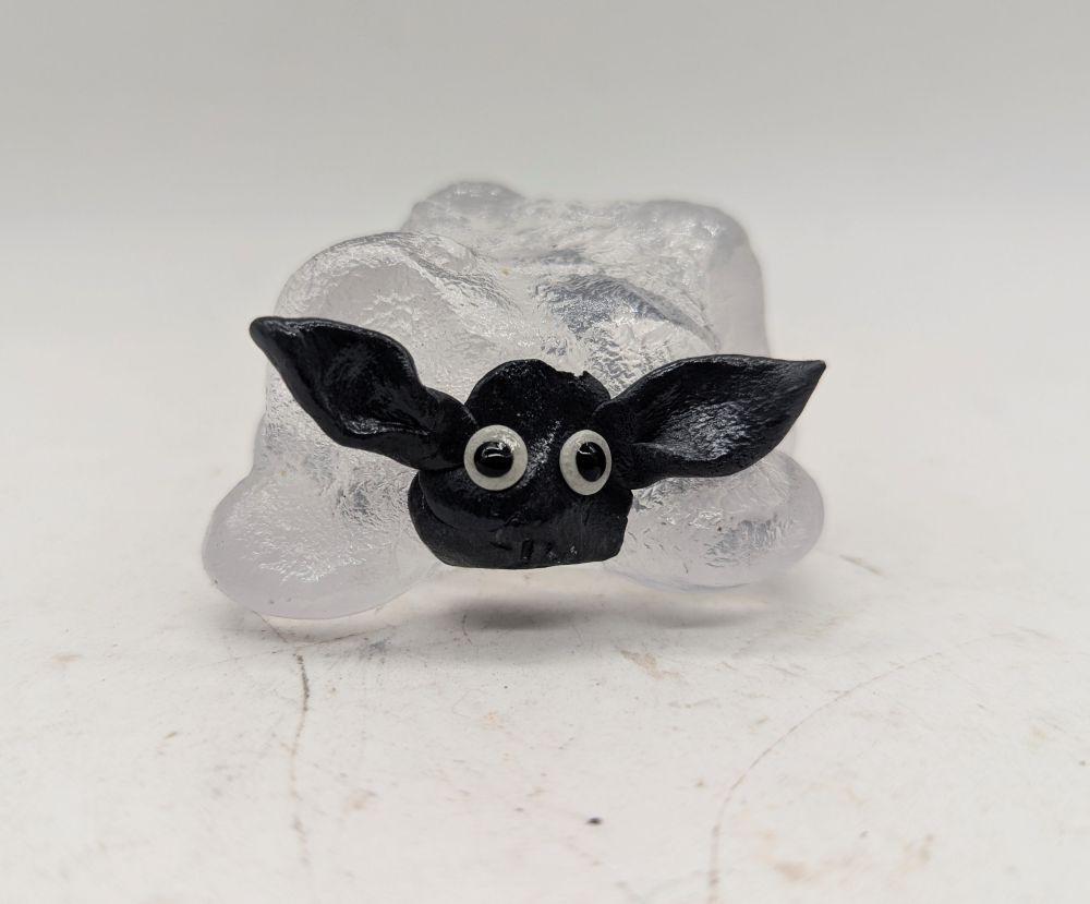 Petit mouton en verre et en argile époxy noir avec des grands yeux, il a l'air un peu bête