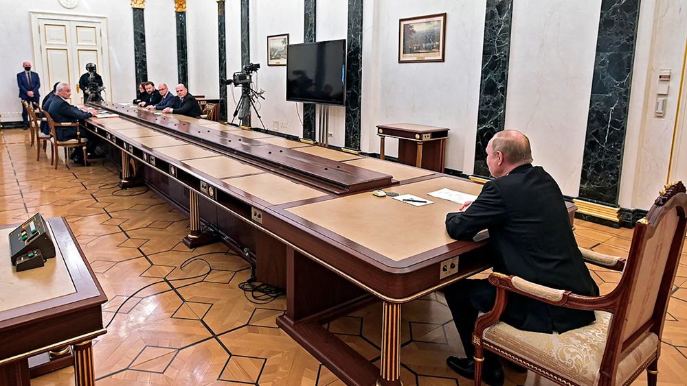 Putin at a meeting where everyone else is at the other end of a comically long table