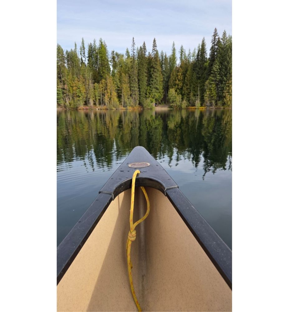 View of canoe bow on a calm tree-lined lake