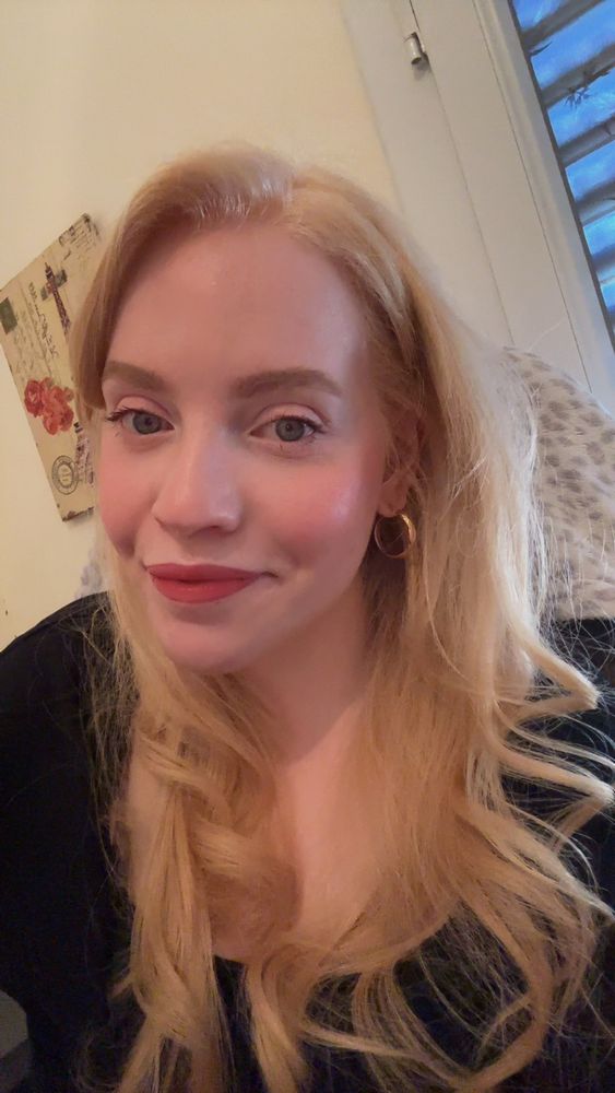 Selfie of me in my room, wearing a black top and golden hoop earrings 