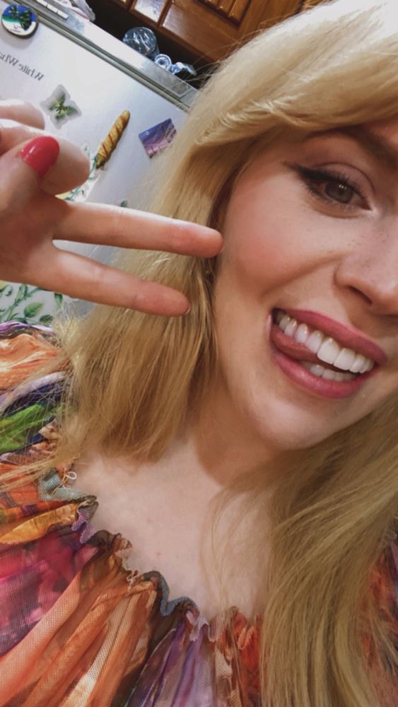 Selfie of me in the same multicoloured top, smiling with my tongue between my teeth and doing a peace sign 
