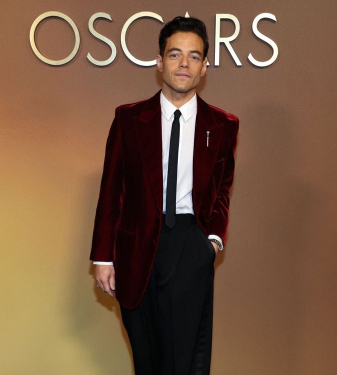 Rami Malek at the Governors Awards in a slim red velvet jacket and skinny tie 