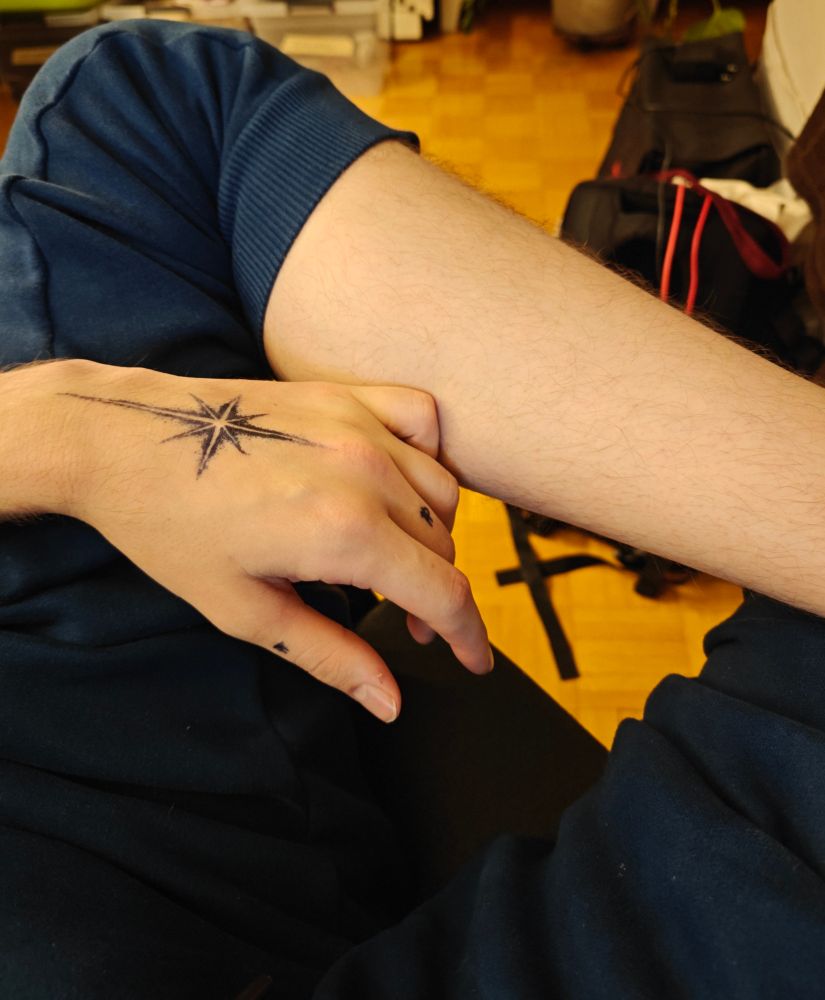 Nilla's left hand with a fake star cross tattoo on the back of his hand as well as two fake nuckle tattoos 