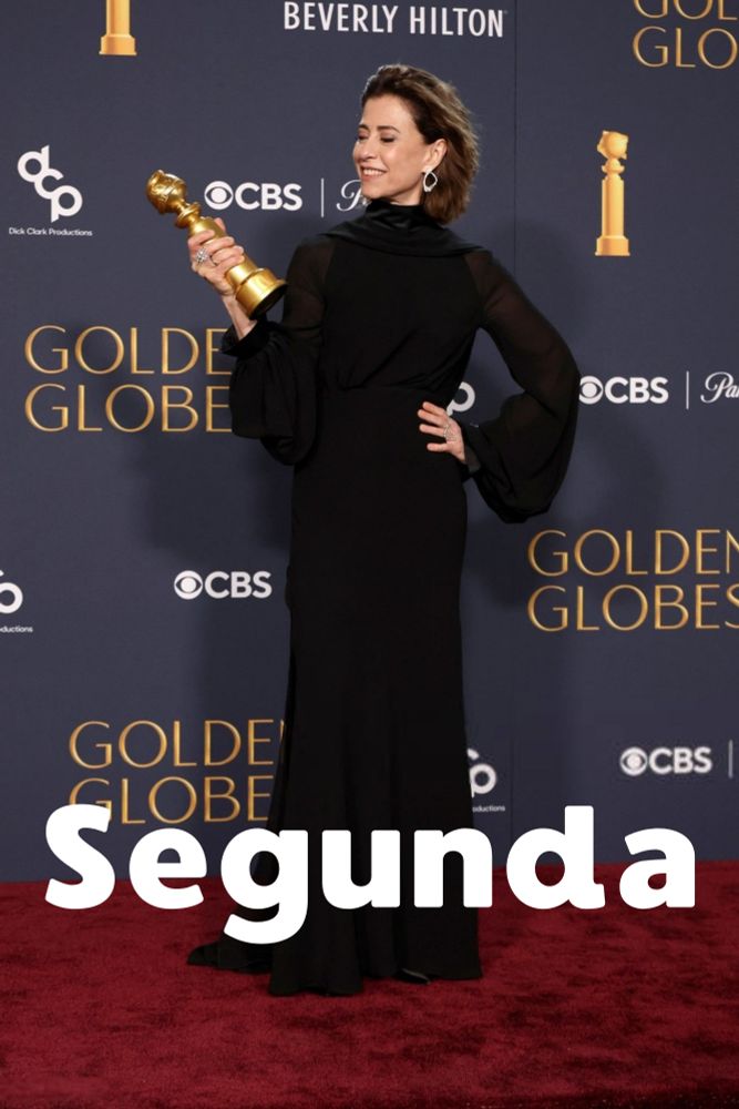A imagem mostra a atriz Fernanda Torres segurando um troféu do Globo de Ouro em um evento realizado no Beverly Hilton. A pessoa está vestida com um vestido longo preto e está posando para fotos em um tapete vermelho. No fundo, há logotipos do Globo de Ouro, CBS, Dick Clark Productions e o nome do hotel Beverly Hilton. A palavra 'Segunda' está escrita em letras grandes e brancas na parte inferior da imagem.