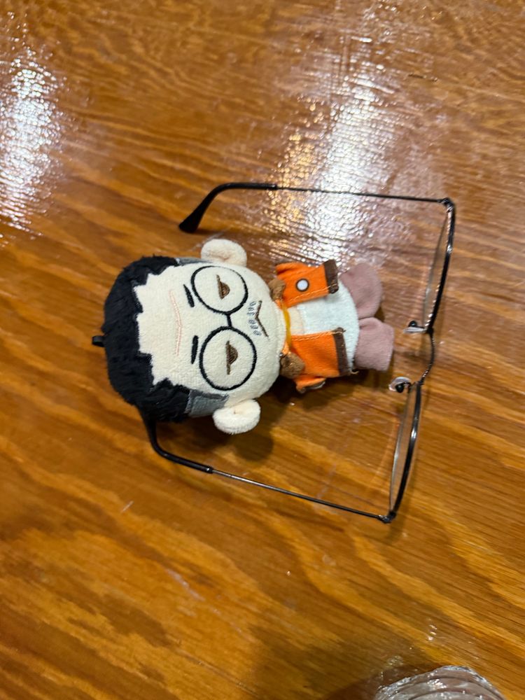 a plush of Kim Kitsuragi laying next to glasses