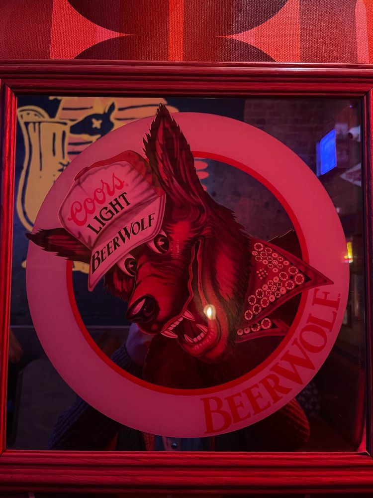 An old coors light branded bar mirror with a smiling cartoon wolf character in a coors hat called BeerWolf