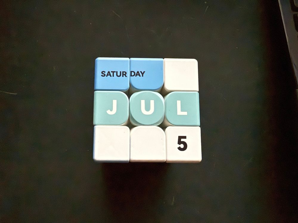a Rubik’s cube arranged so that the panels say “Saturday JUL 5”