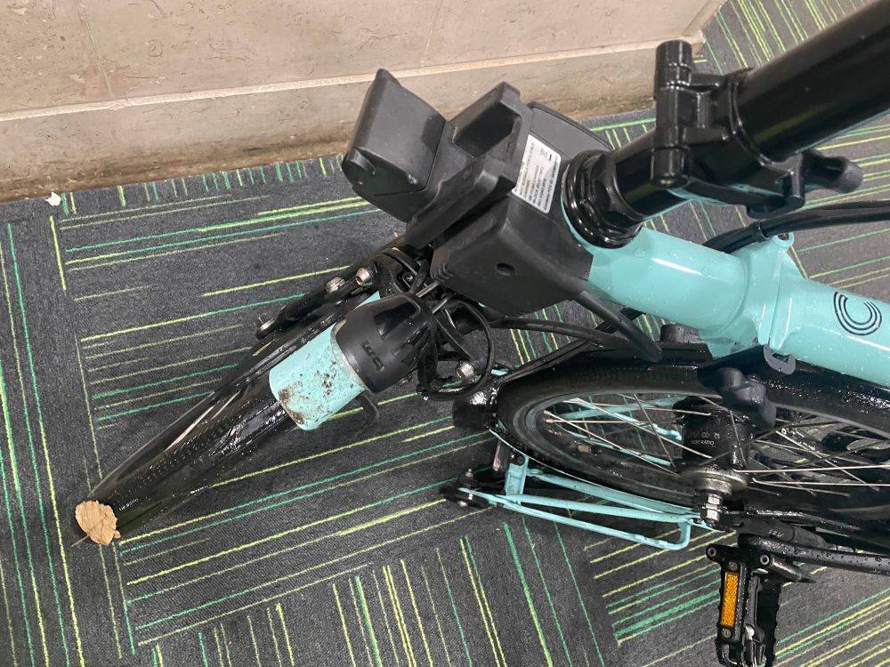 Wet Turkish Green Brompton bike with mud and leaves on it. 