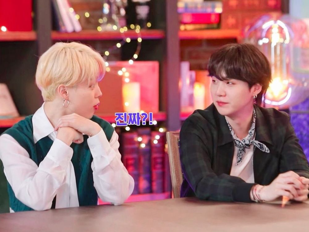 A picture of yoonmin at 2021 bts festa. They’re sitting next to each other at the table, (blonde) mimi is looking at yoongi surprised (the Korean word for “really?” (진짜) is written next to him. Yoongi is looking back at him looking very fond ugh stand up.
